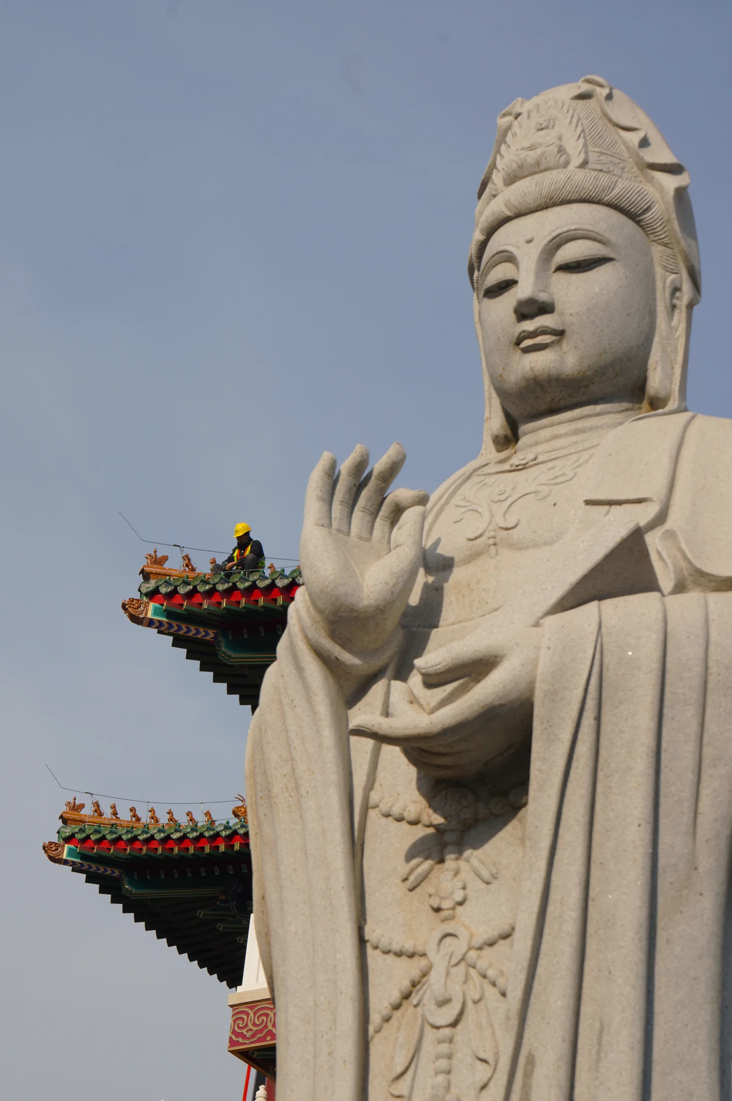 巨大佛像与屋顶上的微小工人